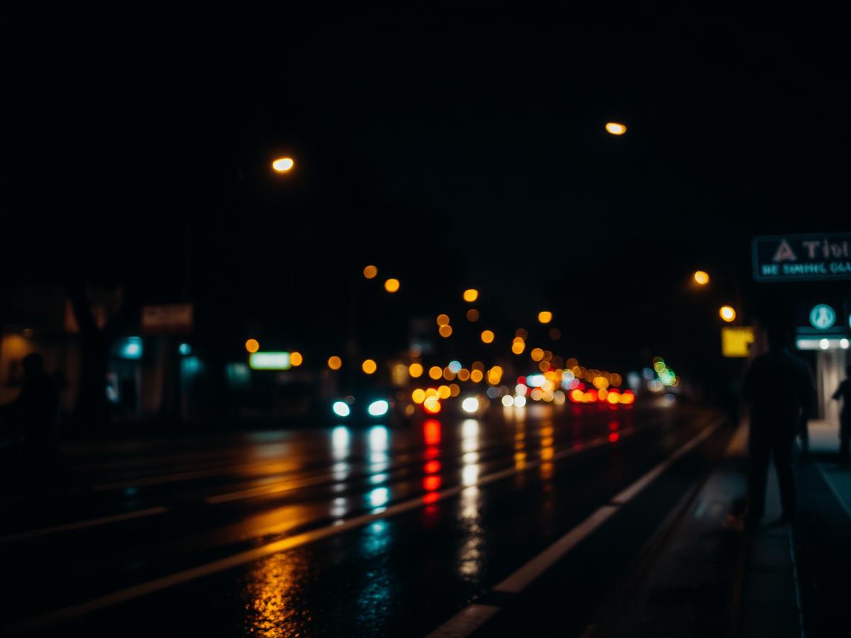 Bengaluru street at night with warm lights and rain reflections