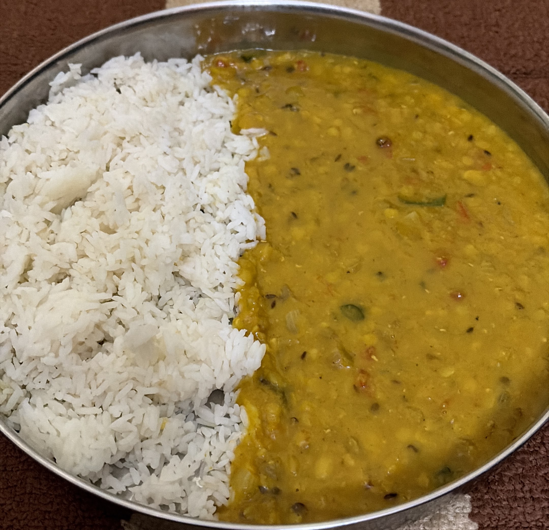 Home cooked dal and chawal on a wooden table by candlelight